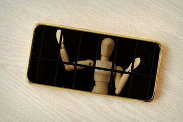 Smartphone with wooden mannequin prisoner behind bars - Technology and mobile devices addiction concept