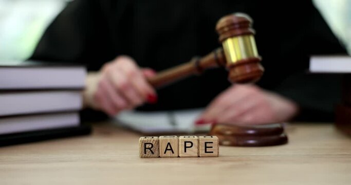 Word rape on wooden cubes near judge in courtroom closeup 4k movie slow motion. Criminal liability for rape concept