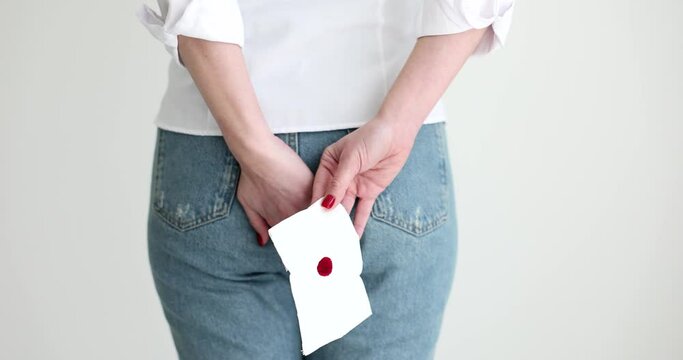 Woman holding onto rectal area with bloody toilet paper back view 4k movie slow motion. Bleeding as complication and symptom of hemorrhoids and colorectal cancer concept