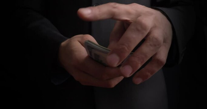 A male hands count a stack of paper bills into one hundred dollar bills. Credit. Cash. Capitalism. Close-up and dark background