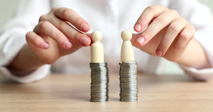 Hands putting female and male wooden figurine on pile of coins closeup 4k movie slow motion. Equal opportunities for men and women at work concept
