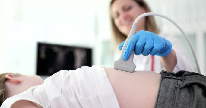 Doctor pediatrician conducting abdominal ultrasound examination of internal organs of child in clinic 4k movie slow motion. Diagnosis of treatment of diseases of gastrointestinal tract in children