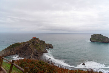 Panoramic view of the touristy Basque coast, in the background the sanctuary of San Juan de Gaztelugatxe located on a hill in the middle of the sea and surrounded by a beautiful coastal landscape.