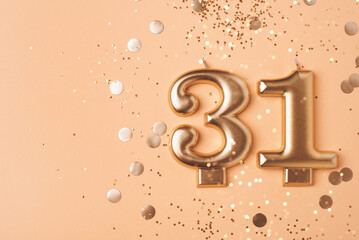 31 years celebration. Greeting banner. Gold candles in the form of number thirty one on peach background with confetti.