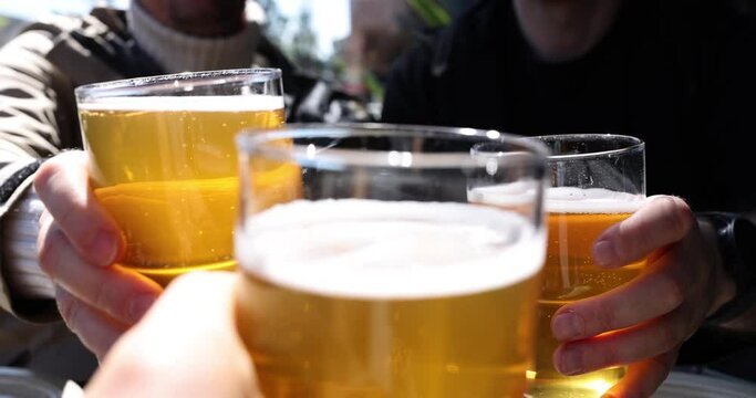 Group of men drinking beer and clinking glasses on street closeup 4k movie slow motion. Oktoberfest beer festival concept