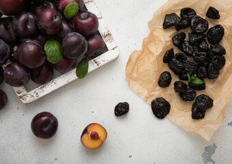 Dried sweet prunes with ripe plums in wooden box on light kitchen background.Macro