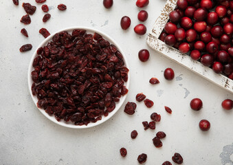 Plate with dried red sweet cranberry with ripe cranberries in wooden box.
