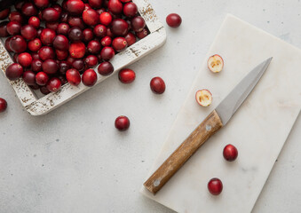 Wooden box with red ripe cranberries and kitchen knife on light background.Top view.