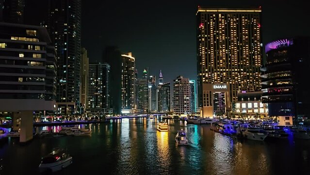 UAE, Dubai - United Arab Emirates 01 April 2024 Time lapse Dubai Marina Waterfront at Night, Glittering night view of Dubai Marina with illuminated buildings and boats.