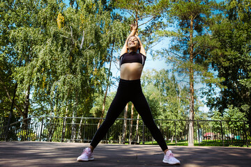 young teenage girl on a summer day in the park is engaged in stretching and sports exercises