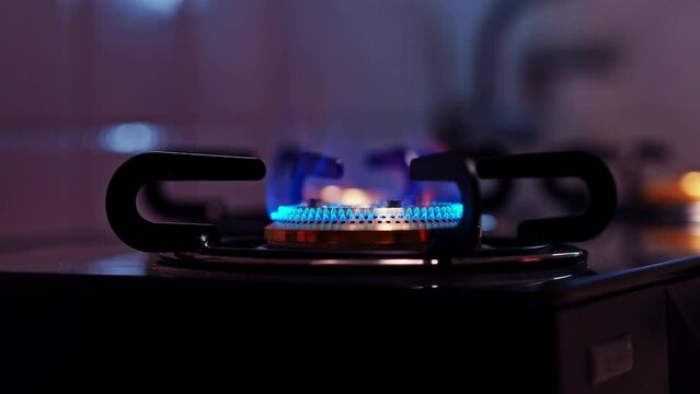 burning gas stove with blue flame in dark kitchen