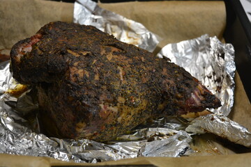 Eating, cooking delicious meat, sheep leg on the bone marinated and baked in the oven. A large piece of lamb arranged on brown parchment paper.