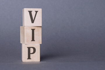VIP text made of wooden cubes on background with a small model houses. image is reflected on the...