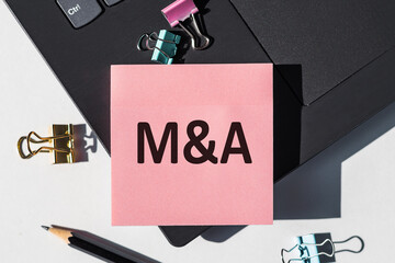 Pink paper stickers with text M and A, business concept. MA - short for mergers and acquisitions