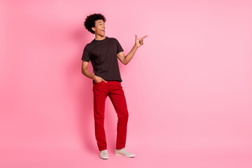 Full length body photo of funny happy man in bright garment direct finger billboard interesting announce isolated on pink color background