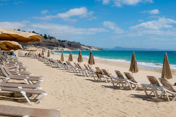 Parasols and deckchairs on a sunny beach awaiting the arrival of tourists.