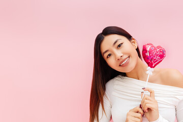 Portrait of cheerful brunette asian lady holding balloon and looking at camera