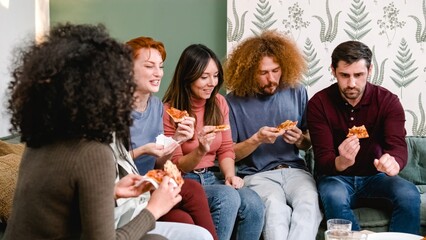 Happy friends enjoying pizza slices in living room during weekend party