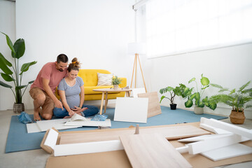 Young pregnant couple assembling furniture arranging the house for the arrival of a new baby. High quality photo