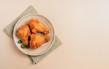 A plate of crispy fried chicken snacks, including nuggets and wings, some dipped in a delicious sauce, on a  background
