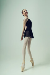 young teenage ballerina poses in a photo studio shows ballet and dance steps