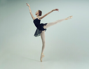 young teenage ballerina in a photo studio posing shows an arabesque