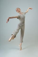young teenage ballerina in a photo studio poses in a fashionable coverall showing elements of dance