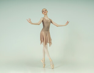 young teenage ballerina poses in a photo studio shows ballet and dance steps