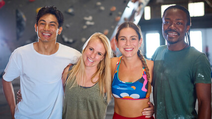 Portrait Of Climbers And Instructors Standing By Climbing Wall In Indoor Activity Centre