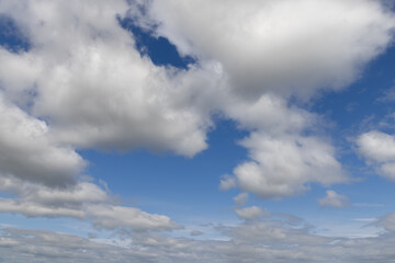 A captivating view of a blue sky with voluminous clouds extending into the horizon, offering a...