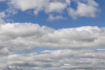 Layers of puffy clouds blanket the horizon under a vast blue sky, creating a serene and dynamic backdrop ideal for replacing the sky in creative projects