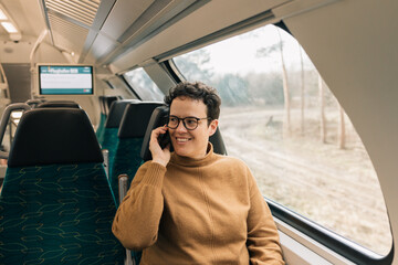 Caucasian woman smiling while talking on the smartphone on the train