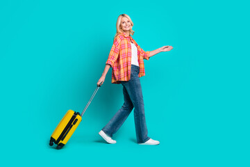 Photo of lovely positive mature woman wear checkered stylish clothes travel trip empty space isolated on cyan color background