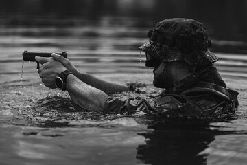 A special forces military man in the water with a pistol, black and white photo.