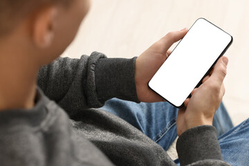 Man using smartphone with blank screen indoors, closeup. Mockup for design