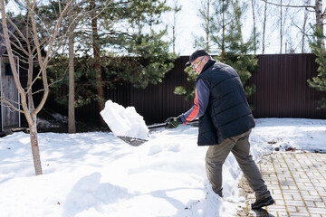 Seasonal work in the garden, a man clears snowdrifts in early spring to get to the tree