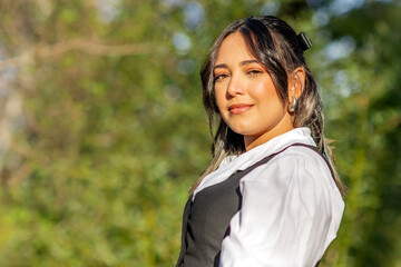 Fototapeta premium Confident professional South American woman in formal suit with lush greenery in the background