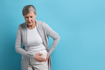Arthritis symptoms. Woman suffering from hip joint pain on light blue background, space for text