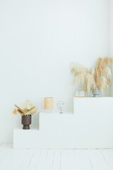 White pedestal with vases and pampas grass palm leaves and lamp