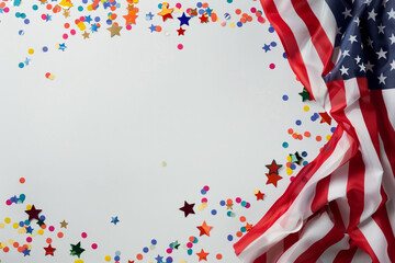 Obraz premium An elegant USA flag draped with grace, with confetti in shapes of stars and stripes floating around it, encapsulating the joy of Independence Day on a white background,