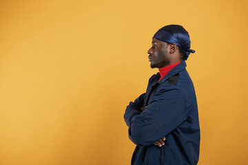 View from the side. Handsome black man is in the studio against yellow background