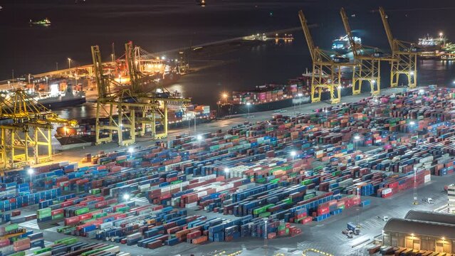 Day to Night Transition Timelapse of Barcelona's Seaport and Loading Docks. Aerial View from Montjuic Hill Captures Cranes and Cargo Containers, Illuminated in the Transition from Sunset to Nightfall