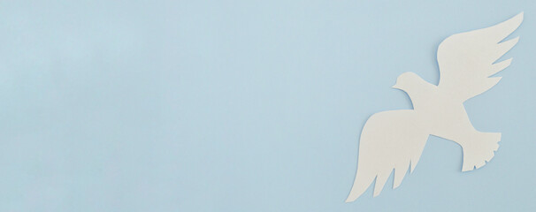 White paper origami bird on blue background. World Day of Peace. Day Against Humiliation. International Day Of Human Fraternity. International Day of Living Together in Peace. Banner