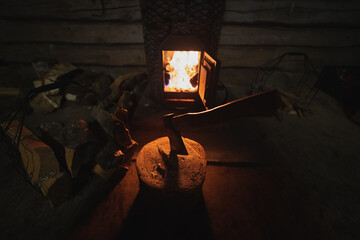 Burning fire in the stove and wood with an ax in the fireplace. Low light photography.