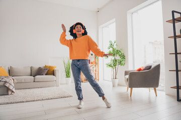 Photo portrait of lovely young lady dance earphones have fun dressed casual orange clothes cozy day light home interior living room