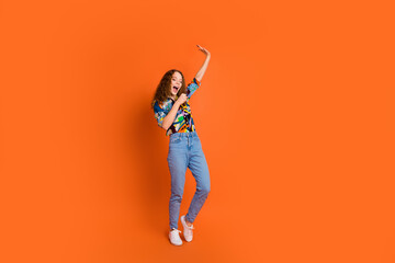 Photo of cheerful charming crazy girl wear trendy print clothes sing song have fun isolated on vibrant orange color background