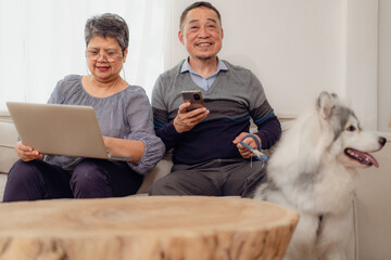 Elderly couple sitting on sofa at home living room relaxing together. Asian senior couple enjoyment...
