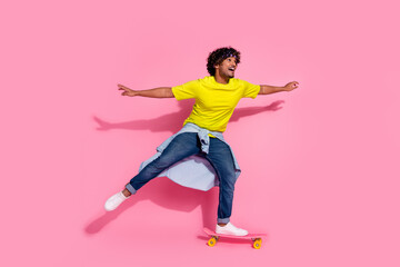 Photo of amazed cheerful glad man wear trendy yellow clothes riding skateboard empty space isolated...