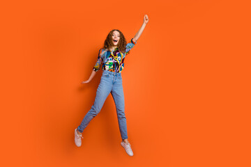 Photo of funky cheerful pretty cute girl wear stylish print clothes arm hold banner empty space isolated on orange color background