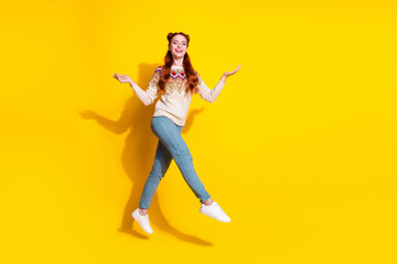 Fototapeta na wymiar Photo portrait of attractive young woman jumping walk raise hands dressed stylish knitted warm outfit isolated on yellow color background